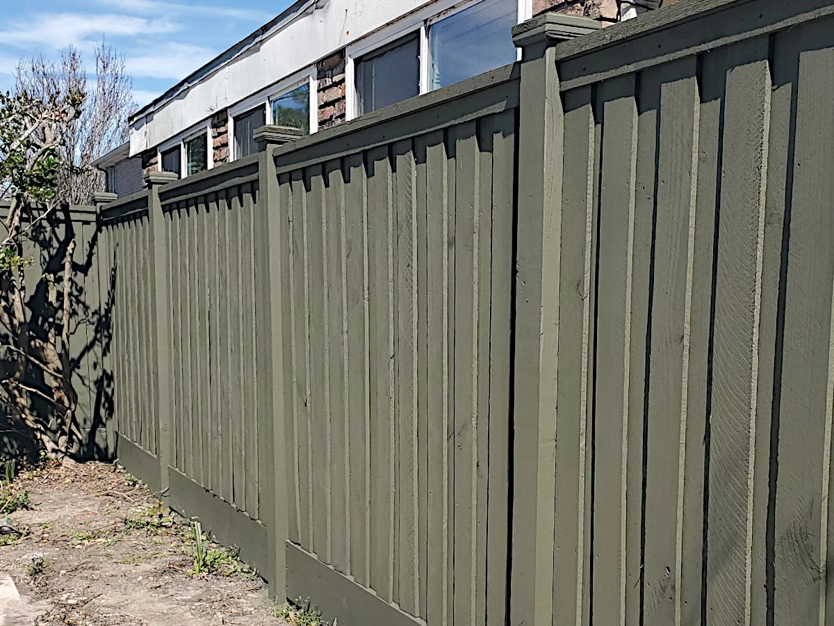 6' board-on-board pine fence in Lakeshore/Lake Vista, New Orleans — suspended between exposed 6" posts with caps, flat top cap, and 12" mudboard at the base.